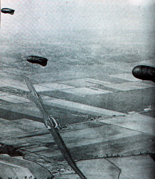 A quelque distance du front, trois ballons Caquot, retenus par le câbles. 